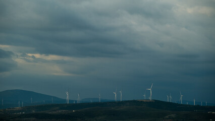 Sustainable energy production with wind turbines on a rugged mountain top surrounded by clouds