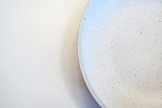 A top-down view of a modern white ceramic bowl with brown speckles, set against a clean off-white background. Perfect for minimalist food photography or lifestyle backgrounds