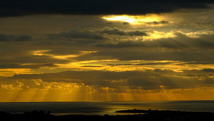 Beautiful sunset at the beach with dancing waves and dramatic clouds reflecting on the water.