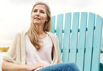 Mature woman, calm and thinking outdoor for holiday, travel and mindfulness by lake with happiness. Female person, peace and zen in nature for vacation, summer and wellness by pond with smile or hope