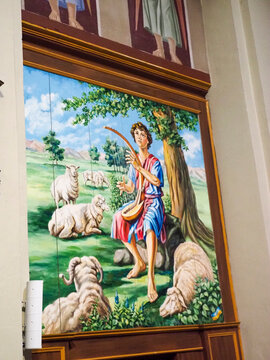 David playing the harp during pastoral scene, surrounded by sheep in a green landscape, depicting a biblical youth shepherd in Calendasco, Italy