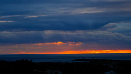 Beautiful sunset at the beach with dancing waves and dramatic clouds reflecting on the water.