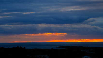 Beautiful sunset at the beach with dancing waves and dramatic clouds reflecting on the water.