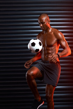 Soccer, ball and black man for trick with sport, physical fitness or skill development with energy. Professional, male player and football by gym door for practice, balance or training for tournament