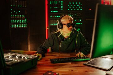 Female programmer hacking computer in dark server room