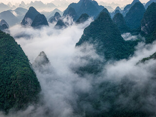 Breathtaking aerial view of karst mountain shrouded in thick white fog in Guilin, China.