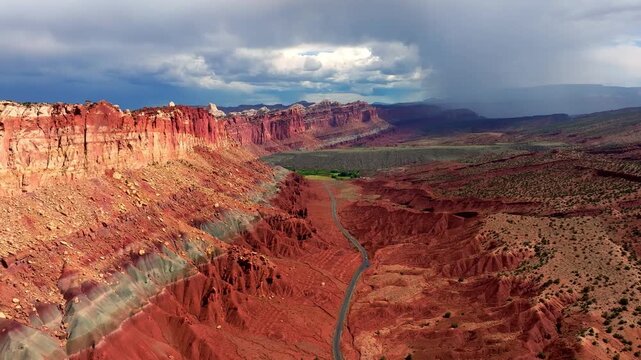 Dramatic aerial view of Capitol Reef National Park's colorful canyons and winding road under stormy skies