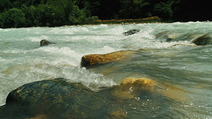 Close up of a wild mountain river with rapids flowing over rocks.