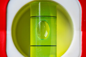 A macro view of a green spirit level vial. The air bubble is perfectly centered between the black marks, indicating a level surface for construction and DIY projects