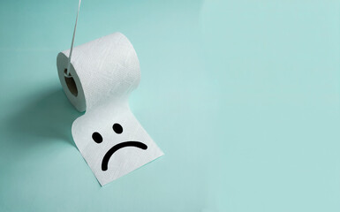 White Toilet Paper Roll with Sad Face Hanging on Blue Background for Digestive Health Concept