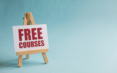 Free Courses Red Text Sign on Small Wooden Easel with Copy Space on Blue Background for Online Education