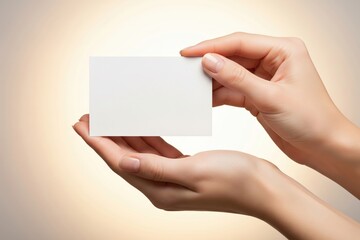 Pretty female hands delicately clutch a blank white card mockup against a soft, warm beige backdrop, perfect for copy space
