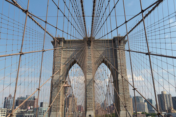 Fototapeta premium The Brooklyn Bridge, built in 1883, is the first suspension bridge constructed of steel and overlooks the skyscrapers of Manhattan, the Big Apple.