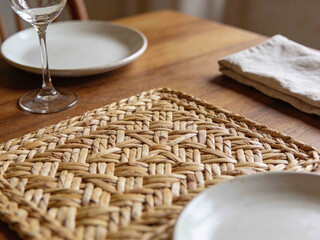Rustic woven placemat on a wooden table with plates and napkin
