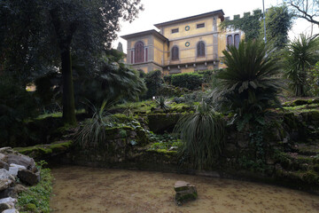 View of the Stibbert Museum from the garden, featuring the neo-Gothic facade, landscaping, trees and stone paths, Florence, Italy