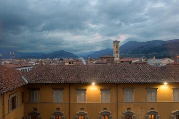 Twilight view over the rooftops of Prato with a bell tower and mountain background, Tuscany, Italy.
