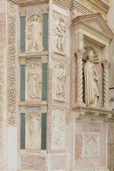 Detail of facade of Oratory of San Bernardino in Perugia, Italy, showcasing Renaissance-style architecture with frescoes and sculptures.