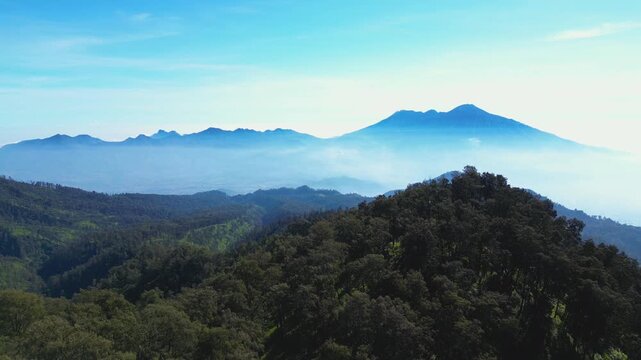 Cinematic drone footage captures majestic Mount Arjuno Welirang range with a hazy sky backdrop in East Java. Ideal for projects related to nature, travel, environment, hiking, and Indonesian volcanoes