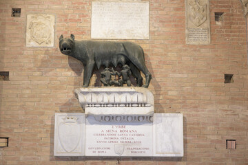 Bronze statue of the She-wolf feeding Senio and Aschio, symbol of Siena, on a marble base with inscription, Palazzo Pubblico, Siena, Tuscany, Italy.