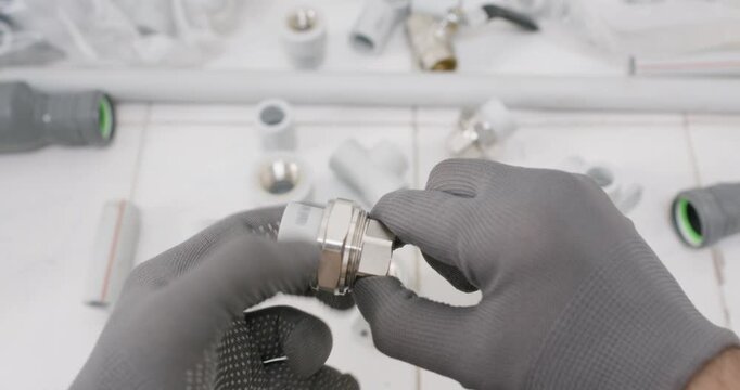 Technician loosens union nut on brass assembly rotating body while reviewing. Plumber gloved hand stabilizes fitting and checks thread wear and verifies seat