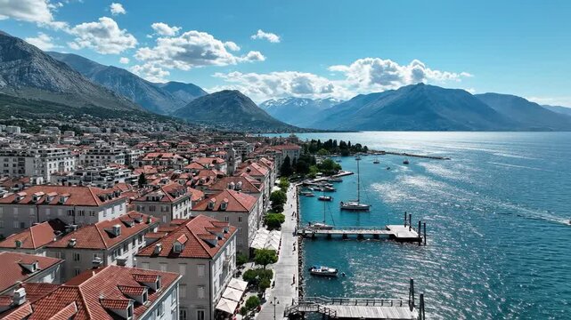 Aerial View of a European Coastal Town with Red Roofs and a Bay Full of Sailboats