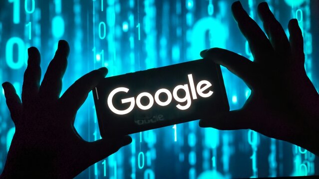 Silhouetted hands holding smartphone with Google logo on screen