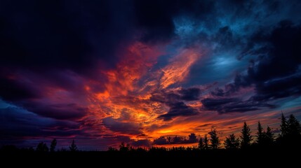 Dramatic sunset sky over forest silhouettes with vivid orange and blue clouds.