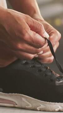 Vertical video: Placing foot on bench hands tying black laces on sneaker pink midsole for workout