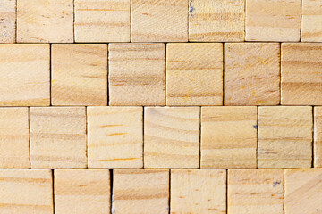 Close-up of small light brown wooden blocks arranged in a staggered grid pattern. The natural wood grain texture is highly detailed, making it ideal for background use