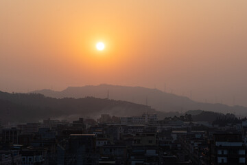 Fototapeta premium Sunset Over Urban Landscape with Hazy Mountains in Background - Huizhou West Lake