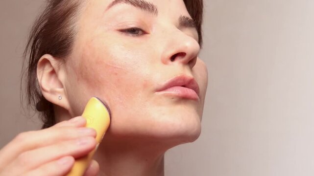 Close up crop footage of Caucasian woman using microcurrent facial toning device at home. Beauty popular device 4k