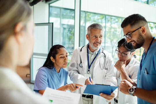 Doctors and nurses discussing patient chart in hospital corridor