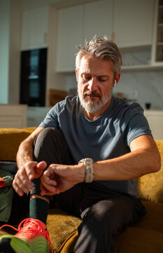 Middle-aged man checking fitness watch at home before workout