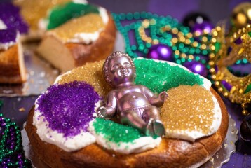 Colorful king cake slice with baby figurine placed on top festive detail for Mardi Gras celebration.