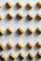 High-angle view of small wooden rectangles arranged in a diagonal grid pattern on a clean white surface. Perfect for background, design concepts, and abstract themes