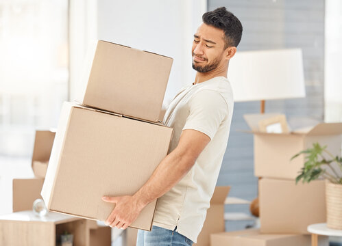 Man, boxes and house moving for property, walking with struggle or heavy cargo in apartment. Male person, carrying and cardboard container in home for real estate, difficult relocation for investment