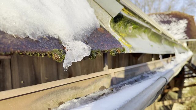 rain gutter with thawing snow and ice
