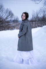 Snow Queen. A young girl in a white dress in the snow. Girl in a white dress. Bride. Winter cold weather. Model. Young woman in winter park.