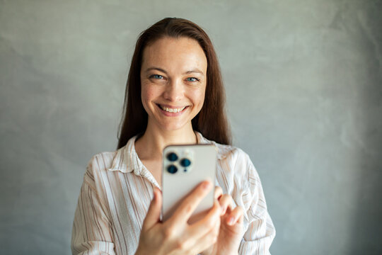 Smiling woman using smartphone at home