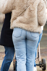 A woman stands outdoors wearing a soft beige faux fur coat paired with classic light blue denim jeans for winter style