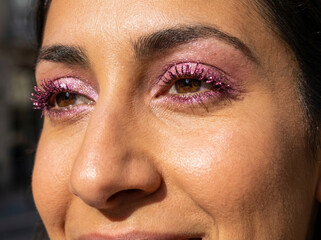 Close up portrait of a woman with a pink glittery trendy makeup 