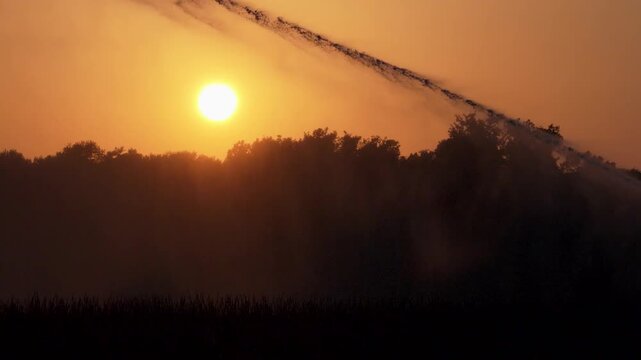 Irrigation of a field in front of a sunset. Agriculture in a hot summer in France