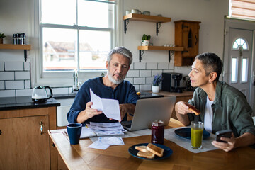 Senior couple managing household finances at kitchen table