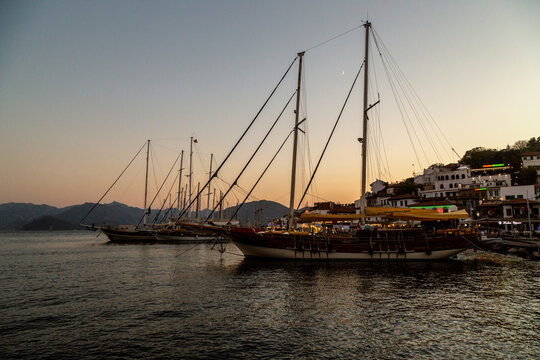 Traditional wooden sailing boats and gulets anchored in a harbor during sunset