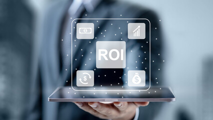 A professional businessman holding a tablet displaying a digital Return on Investment (ROI) interface with financial growth icons in a modern office background