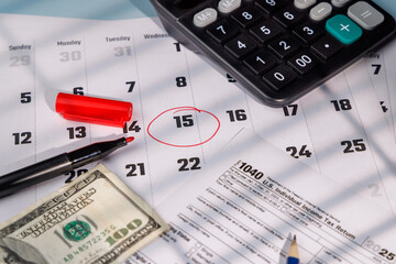 US Tax Day April 15 marked on a calendar with a red circle near IRS Form 1040 and a hundred dollar bill for financial planning ads.