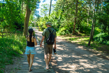 Obraz premium A man and a woman are walking on a wooden boardwalk in a forest