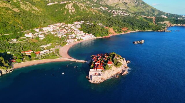 Aerial drone view of the beach and Sveti Stefan Island at sunset. Beautiful architecture and the blue Adriatic Sea. Sveti Stefan, Montenegro.