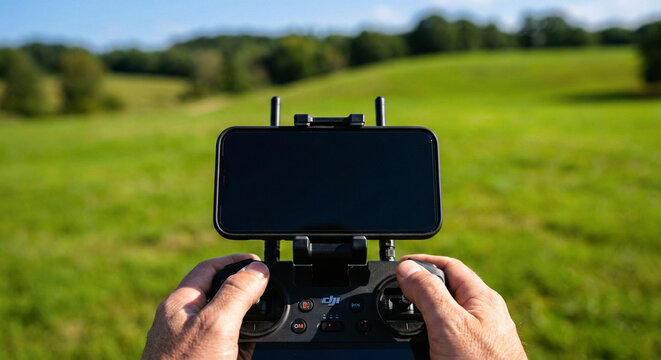 Hands Holding Drone Remote Controller with Smartphone in Green Nature