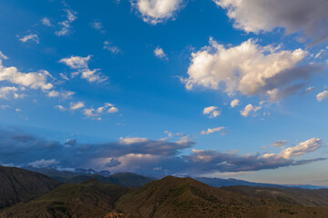 Expansive view of majestic mountains surrounded by soft, fluffy clouds. Natural landscape evokes a sense of peace and tranquility during daytime.